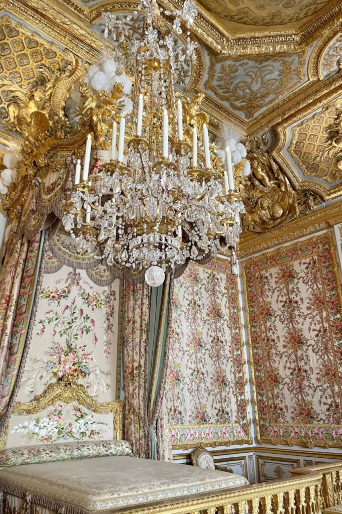 Ornate pastel-toned bedroom at Versailles with antique furniture